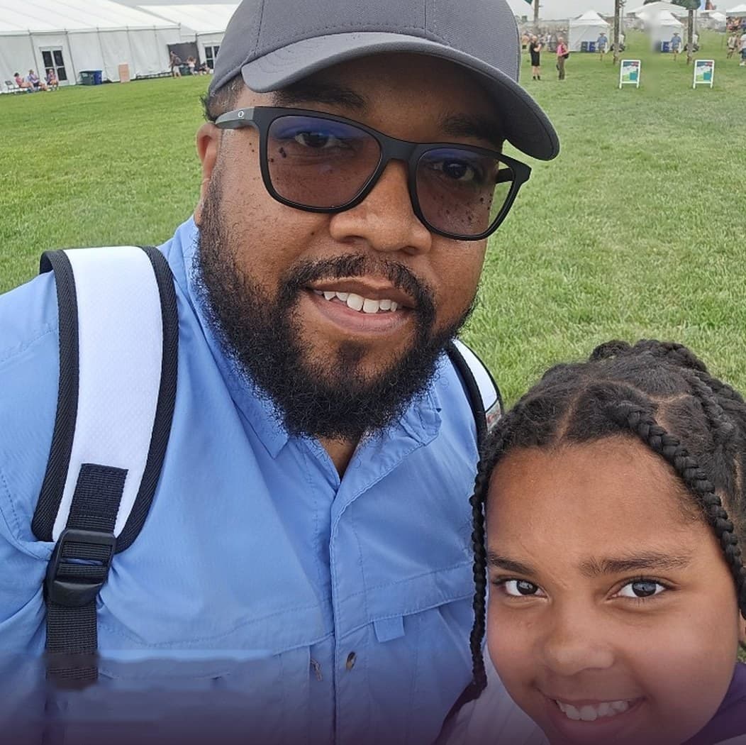 Joseph and his daughter smiling together at an outdoor festival